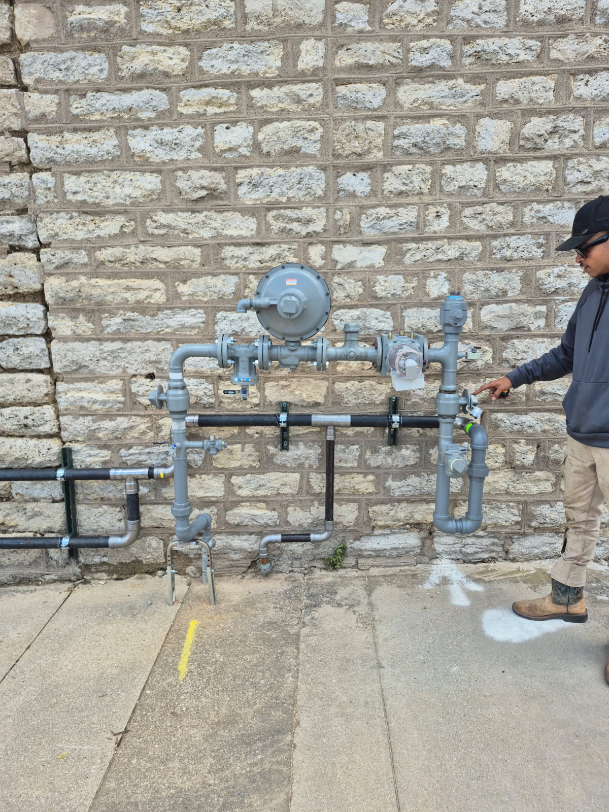 Gas line installation in Weatherford TX performed by Prestige Plumbing, showing a technician inspecting and adjusting exterior gas piping.